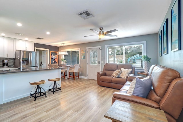 living room featuring sink, light hardwood / wood-style flooring, and ceiling fan