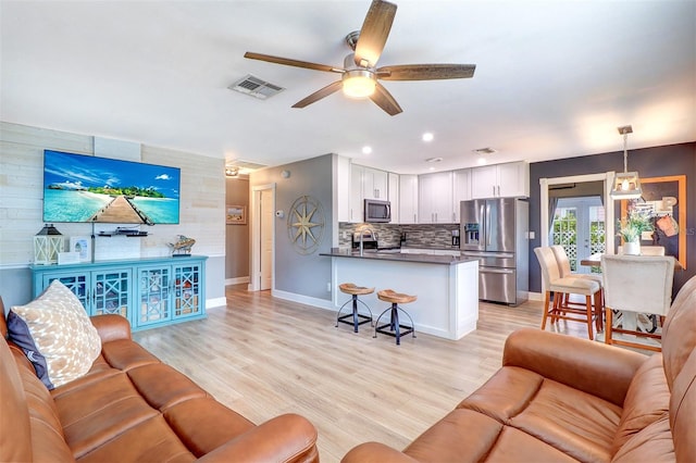 living room with light hardwood / wood-style flooring, ceiling fan, and french doors