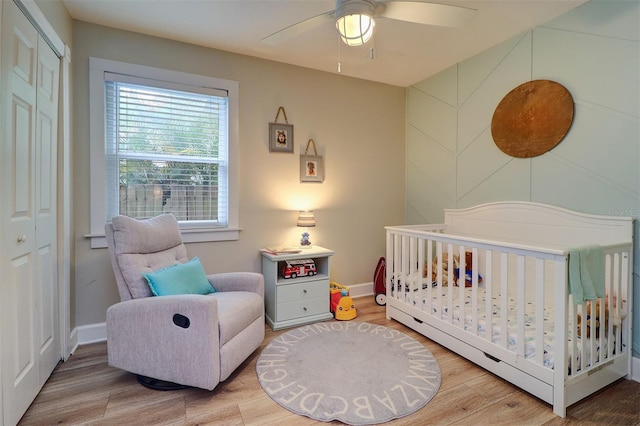 bedroom with a closet, a nursery area, and hardwood / wood-style floors