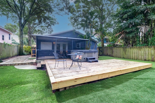 rear view of house with a lawn, a hot tub, a sunroom, and a wooden deck