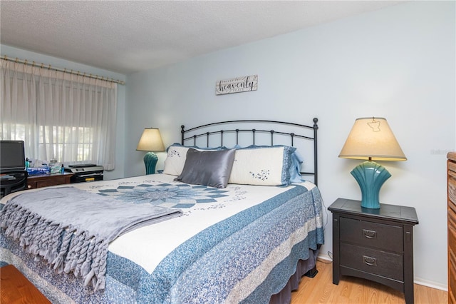 bedroom with a textured ceiling and light hardwood / wood-style flooring