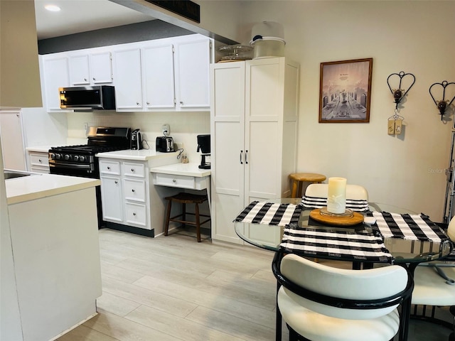 kitchen featuring tasteful backsplash, white cabinetry, light wood-type flooring, and appliances with stainless steel finishes