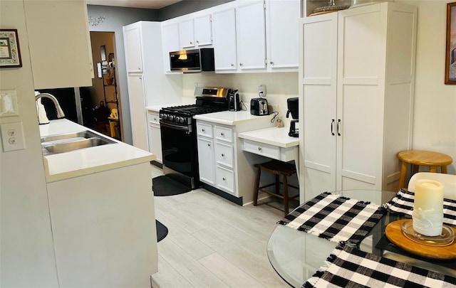 kitchen with sink, white cabinetry, black range with gas cooktop, and light wood-type flooring