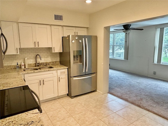 kitchen featuring stove, light carpet, sink, stainless steel refrigerator with ice dispenser, and white cabinetry