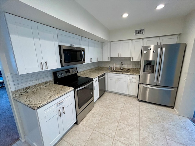 kitchen with backsplash, white cabinets, sink, appliances with stainless steel finishes, and light stone counters