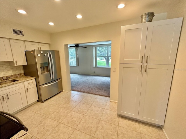 kitchen with white cabinetry, ceiling fan, tasteful backsplash, stainless steel fridge, and light colored carpet