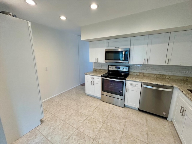 kitchen featuring appliances with stainless steel finishes, backsplash, light stone counters, light tile patterned floors, and white cabinetry