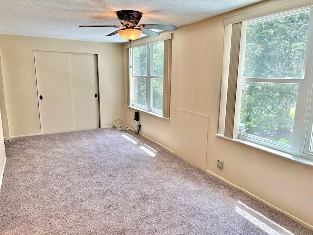 unfurnished bedroom with carpet flooring, ceiling fan, a textured ceiling, and a closet