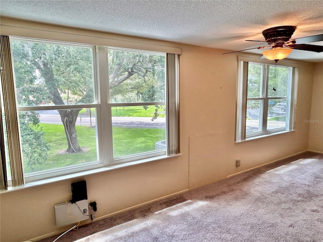 carpeted spare room featuring ceiling fan and a textured ceiling