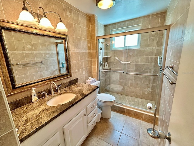 bathroom featuring tile patterned floors, an enclosed shower, toilet, vanity, and tile walls