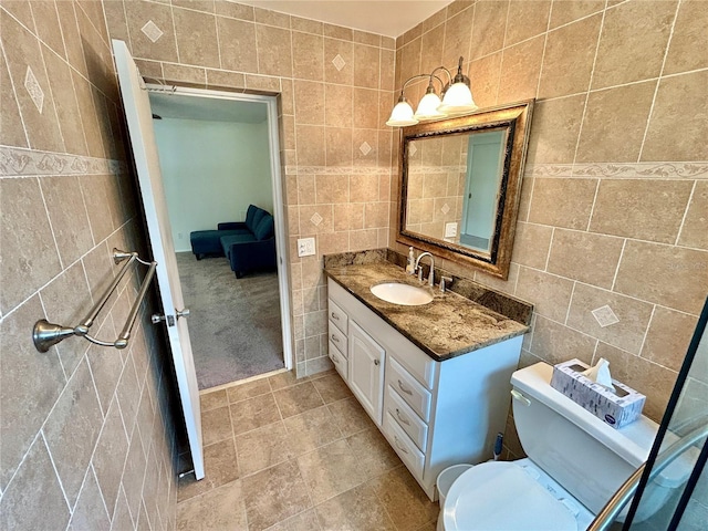 bathroom with vanity, tile walls, and toilet