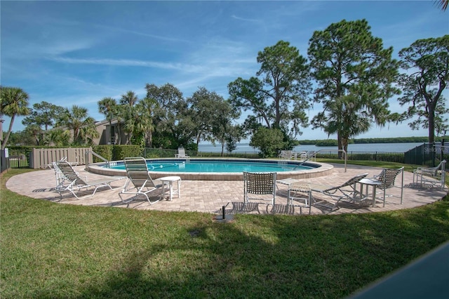 view of pool featuring a yard, a water view, and a patio area