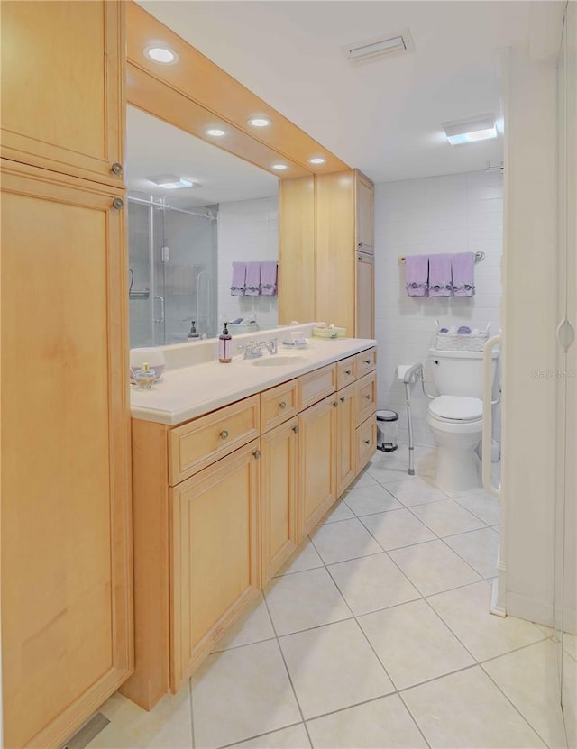 bathroom with tile patterned floors, vanity, tile walls, toilet, and a shower with shower door