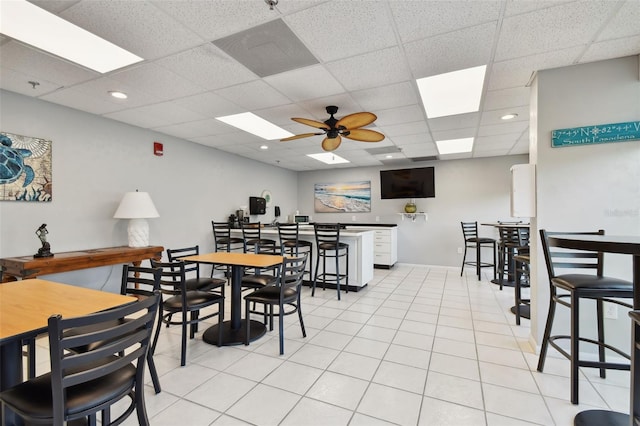 tiled dining area featuring ceiling fan and a drop ceiling