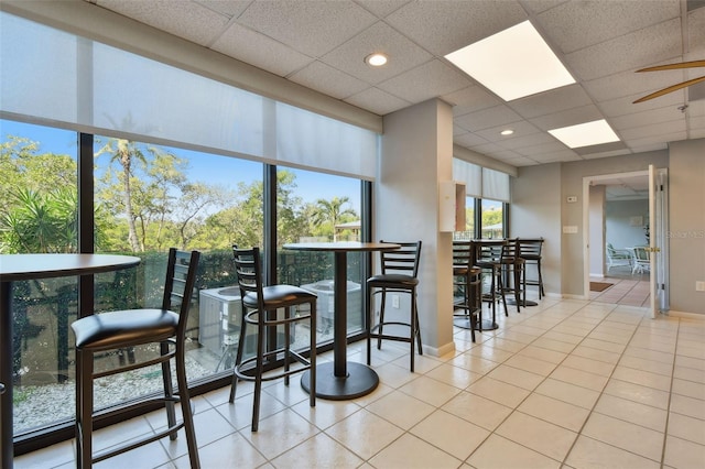 dining area featuring a drop ceiling, tile patterned floors, and ceiling fan