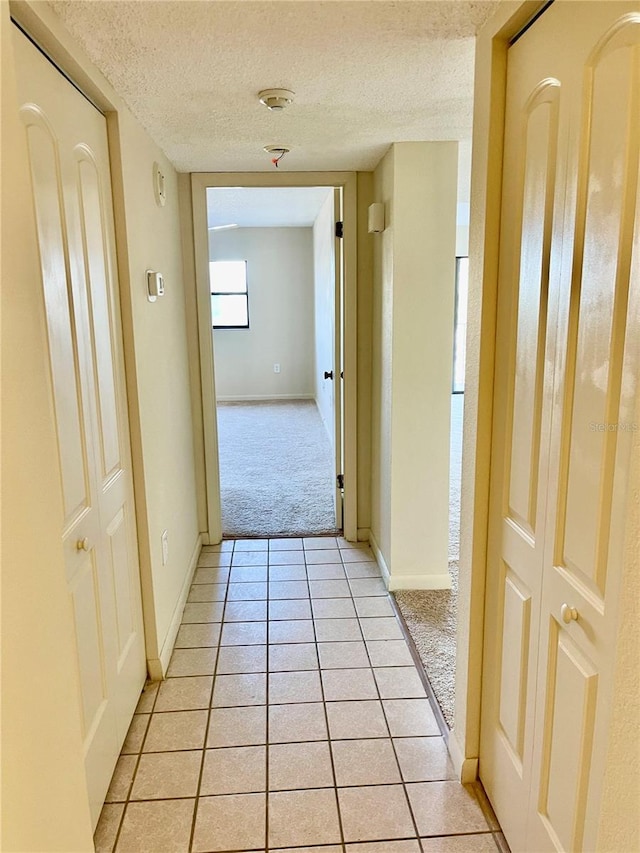 corridor with light tile patterned floors and a textured ceiling