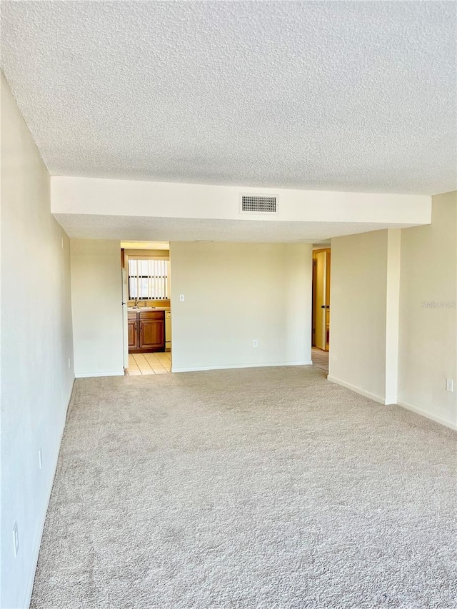 spare room with light colored carpet and a textured ceiling