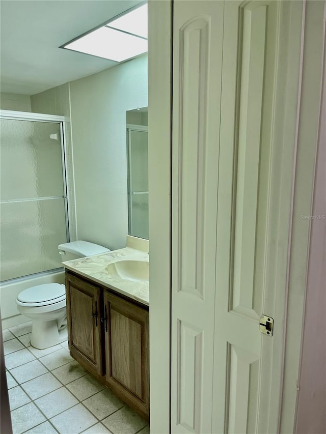 full bathroom featuring shower / bath combination with glass door, tile patterned flooring, a skylight, vanity, and toilet