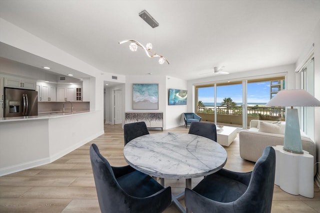 dining room featuring light wood-type flooring, visible vents, and baseboards