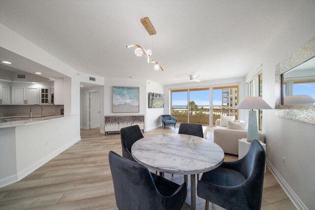 dining area featuring sink, light hardwood / wood-style floors, and a chandelier