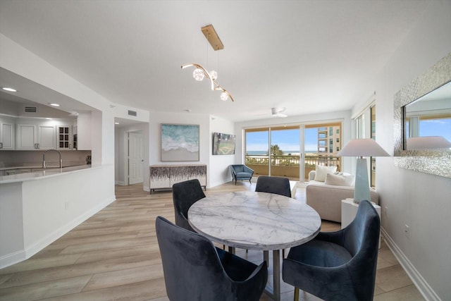 dining area featuring light wood finished floors, plenty of natural light, visible vents, and baseboards