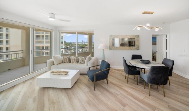 living room featuring baseboards, wood finished floors, and ceiling fan with notable chandelier