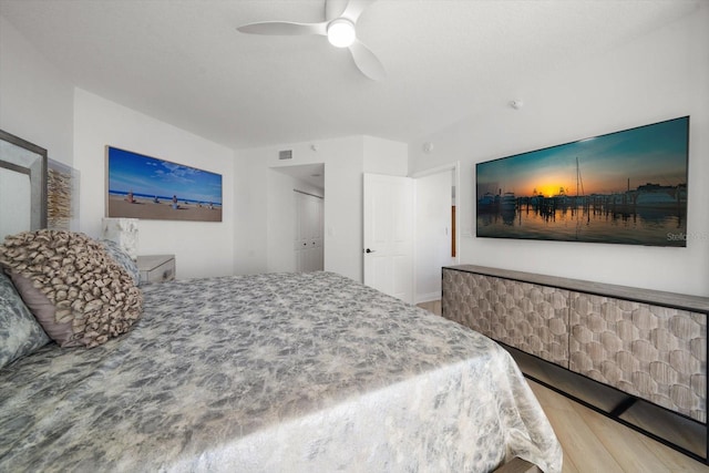 bedroom with light wood-type flooring, ceiling fan, and a closet