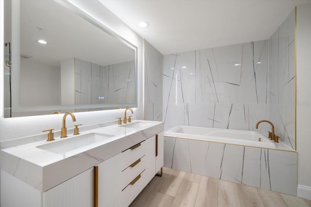 full bath featuring double vanity, wood finished floors, a sink, and tile walls