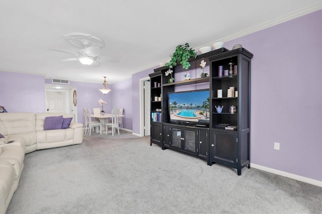living room with ceiling fan, ornamental molding, and light carpet