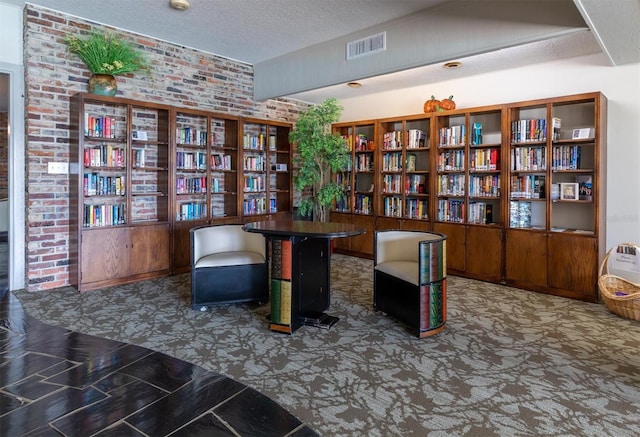 sitting room with a textured ceiling and brick wall