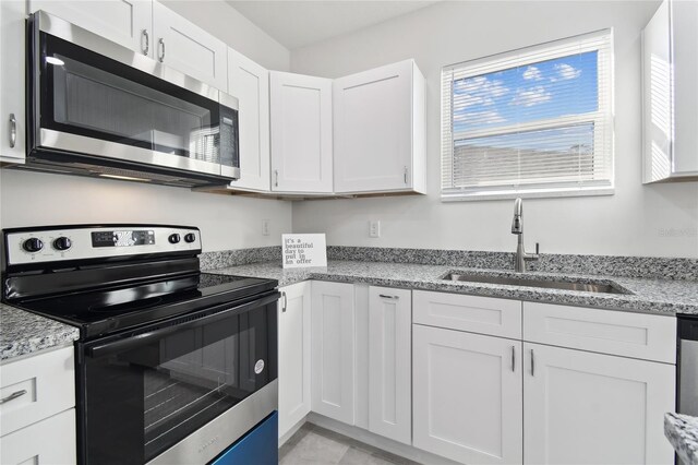 kitchen featuring white cabinets, sink, light stone counters, and stainless steel appliances