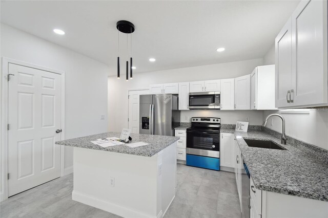 kitchen featuring white cabinets, appliances with stainless steel finishes, a center island, decorative light fixtures, and sink