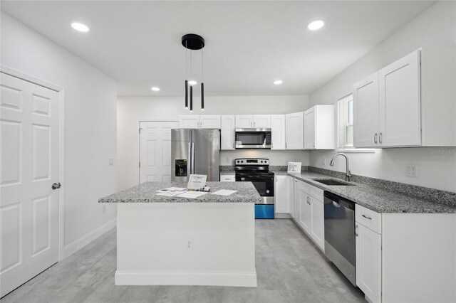 kitchen featuring white cabinetry, stainless steel appliances, a kitchen island, pendant lighting, and sink