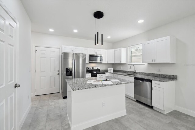 kitchen featuring pendant lighting, a center island, sink, white cabinetry, and appliances with stainless steel finishes