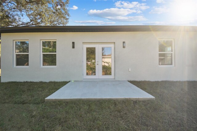 back of property with a lawn, french doors, and a patio area