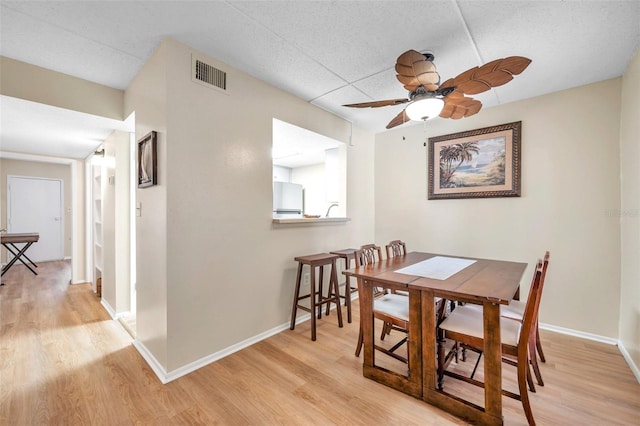 dining space with light hardwood / wood-style flooring and ceiling fan