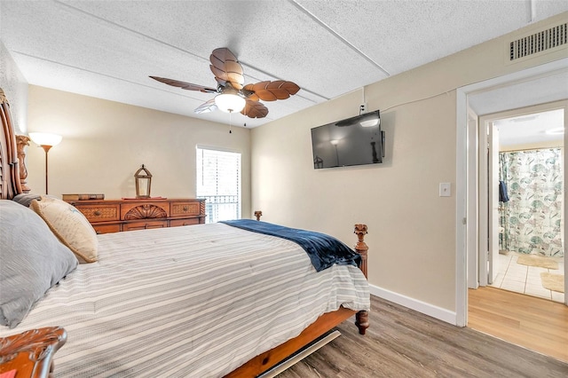 bedroom featuring a textured ceiling, ceiling fan, ensuite bathroom, and hardwood / wood-style flooring