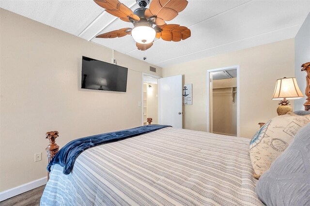 bedroom with wood-type flooring, a walk in closet, ceiling fan, and a closet