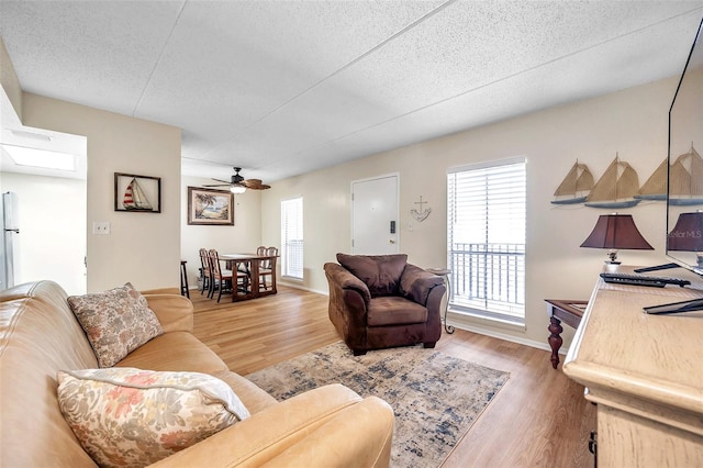 living room featuring ceiling fan, hardwood / wood-style flooring, and a textured ceiling