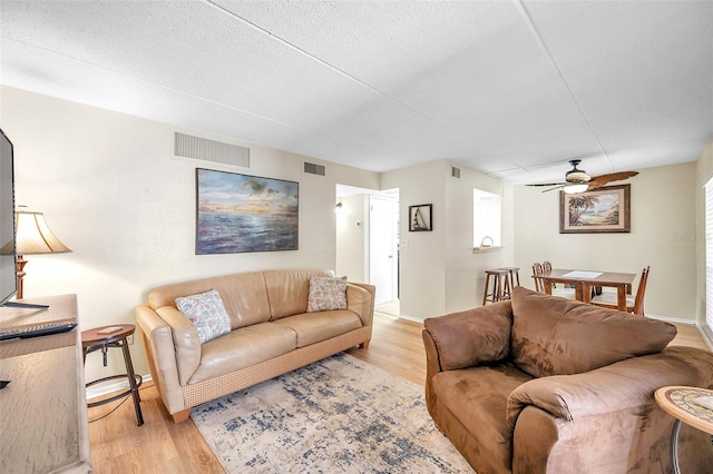 living room featuring a textured ceiling, ceiling fan, and light hardwood / wood-style floors