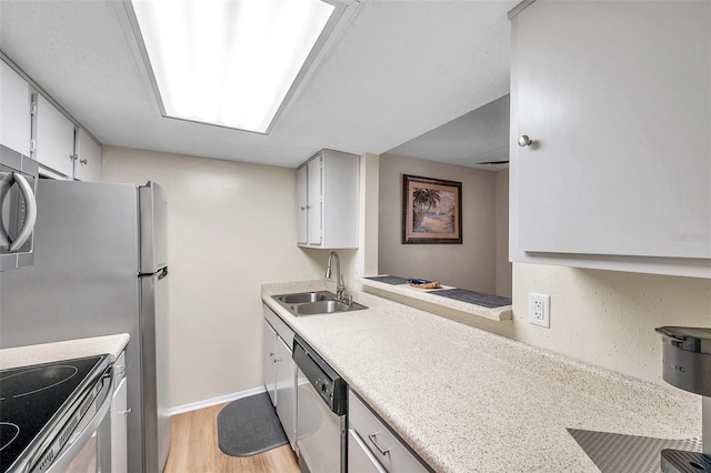 kitchen featuring appliances with stainless steel finishes, light hardwood / wood-style flooring, sink, and white cabinets