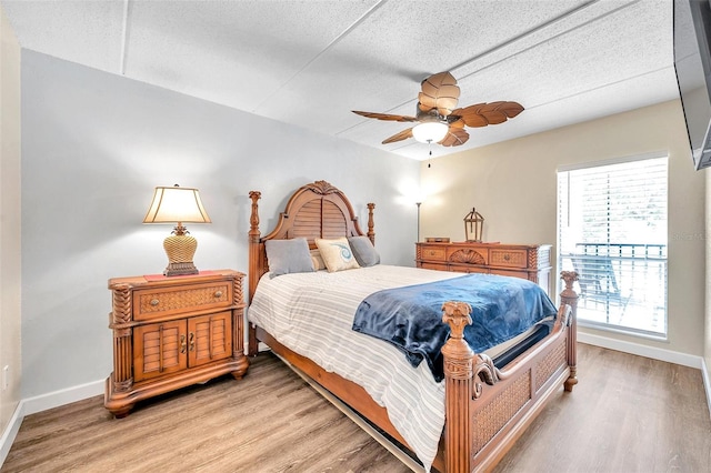 bedroom featuring ceiling fan, hardwood / wood-style flooring, and a textured ceiling