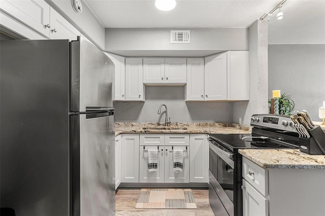 kitchen featuring appliances with stainless steel finishes, light stone counters, white cabinetry, and sink