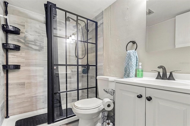 bathroom featuring tiled shower, vanity, and toilet