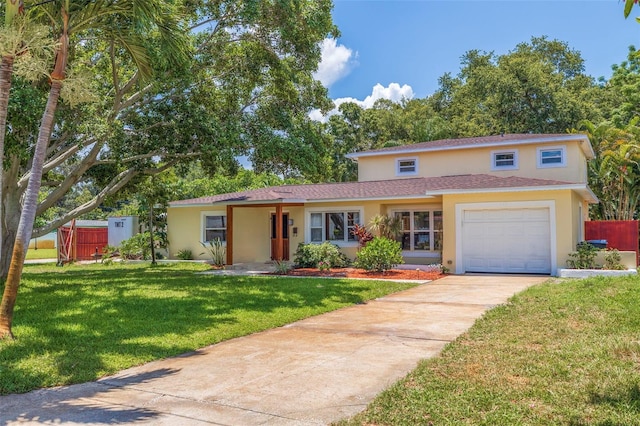 traditional-style house featuring an attached garage, fence, driveway, stucco siding, and a front lawn