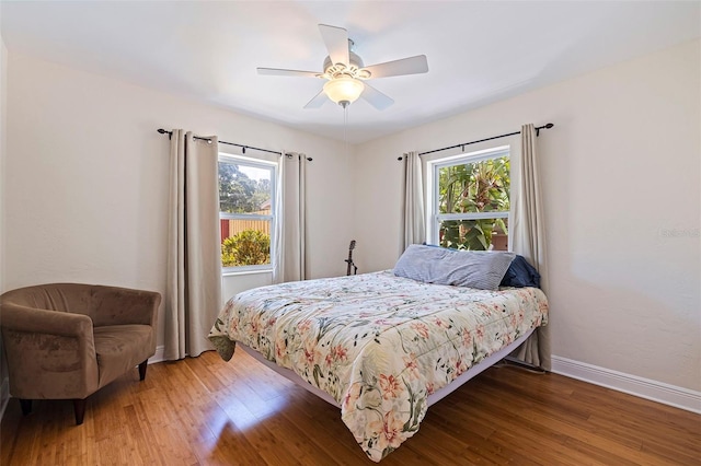 bedroom featuring multiple windows, hardwood / wood-style flooring, and ceiling fan