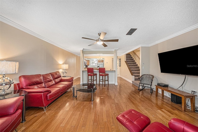 living room with a textured ceiling, hardwood / wood-style flooring, ceiling fan, and crown molding