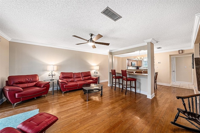 living room with a textured ceiling, ceiling fan with notable chandelier, hardwood / wood-style flooring, and crown molding