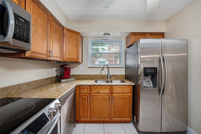 kitchen featuring sink, light tile patterned flooring, stainless steel appliances, and a textured ceiling