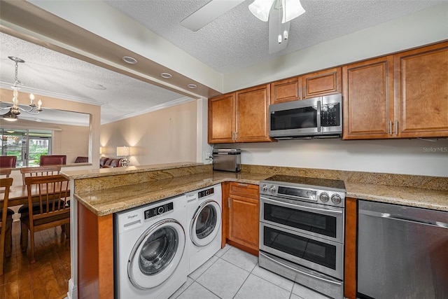 kitchen with kitchen peninsula, a textured ceiling, appliances with stainless steel finishes, and washing machine and clothes dryer